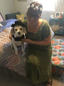 lori sits on bed with her dog oscar in fancy dress