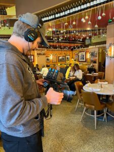cameraman in a busy restaurant looking at the footage on his camera